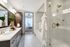En-suite bathroom with a frameless glass walk-in shower, large bathtub, stone floors, and stone-topped dual vanity