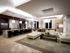 A lounge with stone floors, wood-paneled walls, a white leather sectional seating area, and a catering kitchen with bar stools at a large granite island