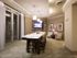 A lounge area with an 8-person dining table, a seating area with armchairs, and a wall-mounted HDTV