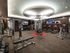 Gym with weight machines, benches, dumbbells, cardio equipment, wood-paneled walls, and carpeted flooring.