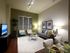 Spacious living room with a taupe accent wall, wood-style floors, a couch, two chairs, a coffee table, and a media console.