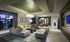 Lounge with floor-to-ceiling windows, a large leather sectional couch, a wall-mounted HDTV, and neutral colors.