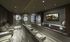 Large, low-lit media room with three terraced rows of large leather armchairs and a blackout curtain along the back wall