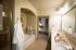 En-suite bathroom with an oval soaking tub under an arched detail, a glass shower, and a dual vanity.