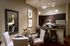 An open-concept kitchen and dining space with a four-person table, white walls, a taupe accent wall, dark wood cabinets, and stainless appliances.