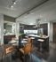 Open-concept kitchen with glass dining table and orange chairs. The kitchen island has a bar with barstools, and the appliances are stainless steel. There is a dry bar with a mirror.
