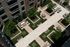 Aerial view of garden courtyard with white and beige walkways leading to seating areas with brown and white tables and chairs. Apartment homes with balconies surround the courtyard and trees line the seating areas.