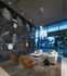 Lobby seating area with high ceilings, floor-to-ceiling windows, a white leather sectional, and leather armchairs next to a full-height black marble accent wall with white vases placed into alcoves