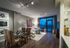 Open-concept living and dining room with high ceilings, full-width floor-to-ceiling windows, wood-style floors, a dry bar, and a taupe accent wall