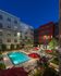 Inner courtyard with landscaped pool surrounded by lounge chairs and red umbrellas.