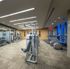 Gym with weight machines, dumbbells, treadmills, ellipticals, floor-to-ceiling windows, and carpeted floors.
