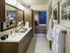 Bathroom adjacent to the master bed with a white quartz dual vanity countertop, white marble-style floors, and dark wood cabinetry.