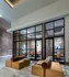 Lobby space with two modern couches next to a wall of windows looking into two conference rooms, one with 6 chairs and one with 4. There is an HDTV visible on the wall of the larger conference room.
