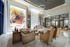 Spacious lobby with high ceilings, floor-to-ceiling windows, marble floors and wall cladding, colorful modern art, a concierge desk, and multiple sitting areas with couches, armchairs, and coffee tables.