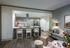Open-concept living and kitchen space with dark wood-style floors, a large peninsula with an electric range and stainless steel overhead hood, and ash-blond wood cabinets.