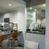 A kitchen and dining area with gray quartz countertops, a dry bar with a mirror, white handleless cabinets, and stainless steel appliances.