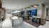 Clubhouse dining area including a catering kitchen with two ovens, a gas stove on a large island with 7 barstools, and 3 dining tables accommodating 4 to 8 chairs. The large floor-to-ceiling windows have been slid back to allow access to an outdoor seating area with a firepit.