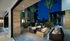 Outdoor firepit and lounge area adjacent to the indoor clubhouse with full-length windows that slide away to create an indoor-outdoor space. There are two wicker couches on opposite sides of the firepit.