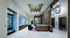 Seating area between an elevator bank and a glass-walled conference room, with armchairs and a large banquette couch.