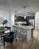 Open-concept kitchen with ash-gray wood-style floors, dark modern wood cabinets, stainless steel appliances, granite countertops with a peninsula.
