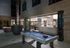 Outdoor billiards table next to the firepit and adjacent to the indoor clubhouse with full-length windows that slide away to create an indoor-outdoor space.