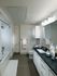 Spacious bathroom with warm gray tile floors, a large soaking tub with a shower curtain, white cabinets, black quartz countertops, and a large framed mirror.