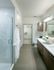 Bathroom featuring a frameless glass door walk-in shower, a dual vanity with dark wood cabinets and a white quartz countertop, and a walk-in closet.