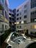 A courtyard surrounded by the interior walls of the apartment complex, with balconies overlooking the landscaping, patio tables and chairs, and dining cabana.