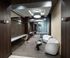A carpeted hallway-like work area furnished with armchairs, two-person tables, and a desk along the wall with outlets.