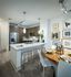 Open-concept kitchen and dining space with a 4-person dining table, ash-gray wood-style floors, dark modern cabinets, stainless steel appliances, and white quartz countertops.