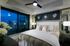 Bedroom featuring a large bed and dresser, recessed ceiling with a fan, full-width window, and white walls with a gray accent wall.