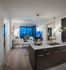 Open-concept kitchen, dining, and living space with 10-ft floor-to-ceiling windows on two walls, ash-gray wood-style floors, dark modern cabinets, stainless steel appliances, granite countertops, and a spacious living area.