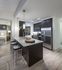 Kitchen with modern dark wood cabinets, stainless steel appliances, granite countertops, ash-gray wood-style floors, and a peninsula with three barstools and an undermount sink.