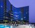 Elevated pool deck with three cabanas and 10 in-pool lounge chairs in front of the backdrop of the upper floors of Buckhead Village, which curve around the pool deck and reflect the dark blue dusk sky.