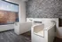 Pet washing room with two large tubs and detachable sprayers in front of a grey accent wall. There is a large window facing an outdoor seating area.