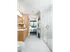 Spacious bathroom with walk-in glass shower, white marble floors and tiling, light wood cabinetry and a large vanity area with a white marble countertop.
