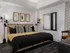 Bedroom with king-sized bed, dresser, armchair, dark wood-style floors, white walls, and recessed ceiling.