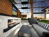 Landscaped outdoor lounge area with couch, coffee table, double-sided fireplace and flat-screen TV.