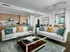 Open-concept living room with two large couches, a coffee table, dark wood-style floors, and white walls.