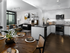 Open-concept dining and kitchen space with a round dining table, stainless appliances, raised ceilings, dark wood-style floors, and floor-to-ceiling windows