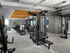 Indoor gym with weight machines, treadmills, ellipticals, stationary bikes, benches, a flat-screen TV and windows on two walls.