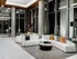 Lobby seating area with two large, curved white couches, modern coffee tables, high ceilings with full window walls and white marble floors.