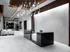 Lobby space with black marble concierge desk, white marble floors and walls, modern silver chandelier, and seating area