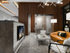 Private meeting area with a glass-walled conference room and a seating area with dark wood-paneled walls, a brown leather couch, two chairs and a flat-screen TV.