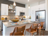A bright kitchen with stainless steel appliances, white cabinets, built-in shelves, dark wood-style floors, and an island with three barstools.