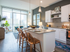 An spacious open-concept kitchen and living space with white cabinets, dark wood-style floors, and full-width floor-to-ceiling windows.