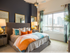 Spacious bedroom with a large bed, full-width window, white walls with a navy accent wall, and beige carpeting.