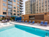 A 90-inch TV overlooking a row of lounge chairs and the shallow end of the pool.