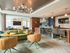 A bright lounge space with large windows, colorful leather couches and armchairs, a bar with an HDTV, a see-thru fireplace, wood-paneled walls, and modern light fixtures.