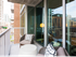 A balcony with brushed silver metal railings that fits two armchairs and a side table, with full-width floor-to-ceiling windows behind.
